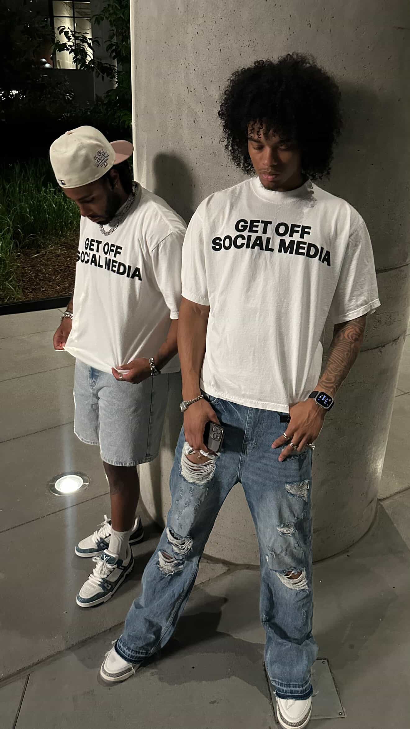 Models wearing Get Off Social Media tees outside at night
